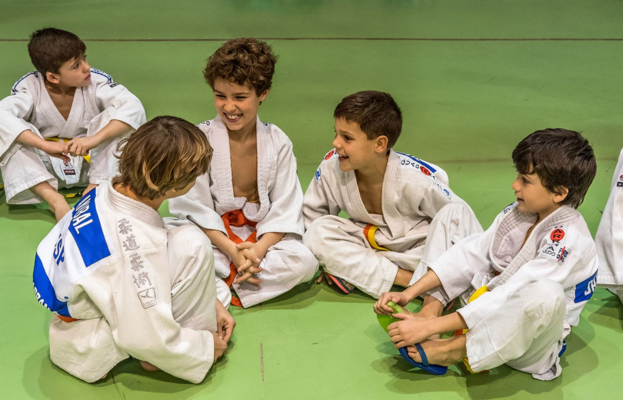 Niños practicando judo sentados sobre el tatami